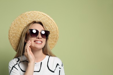 Photo of Beautiful young woman wearing straw hat and sunglasses on light green background, space for text. Stylish headdress