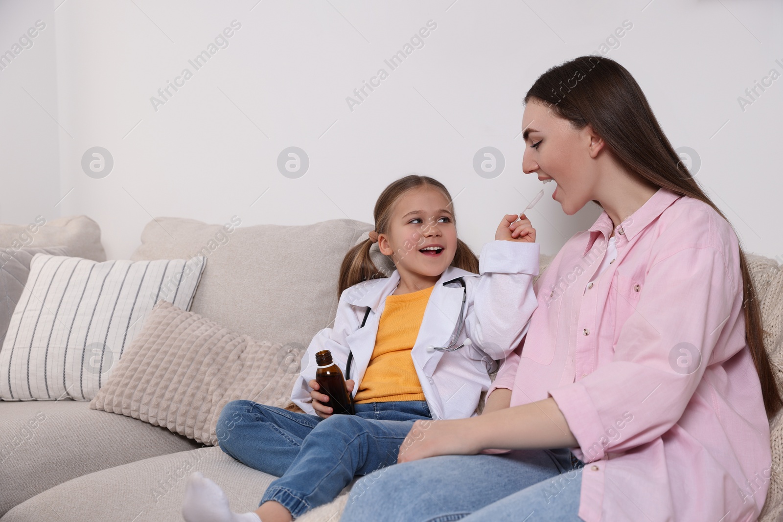 Photo of Little girl playing doctor with her mother at home. Space for text