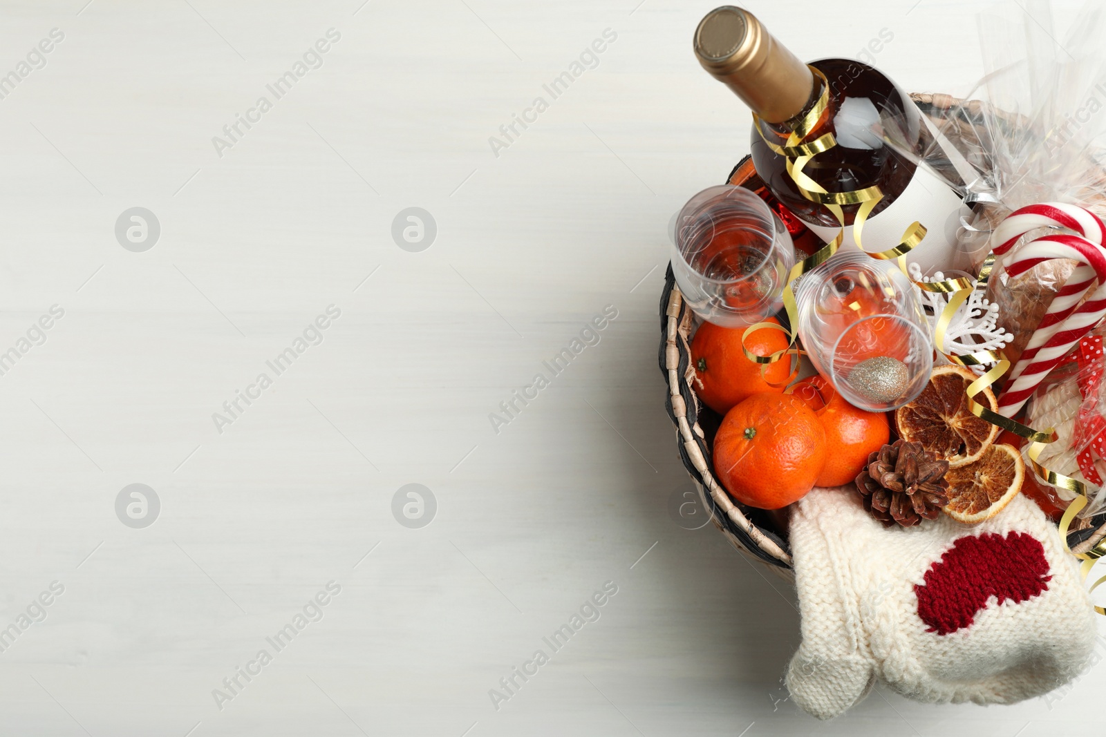 Photo of Wicker basket with Christmas gift set on white wooden table, top view. Space for text