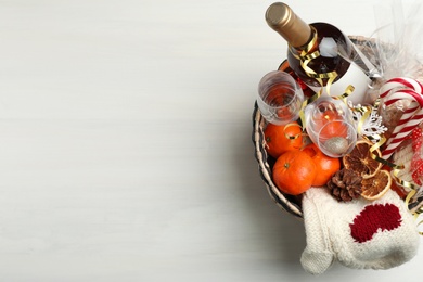 Photo of Wicker basket with Christmas gift set on white wooden table, top view. Space for text