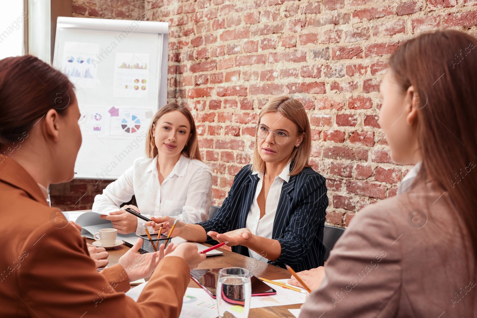 Photo of Businesswoman having meeting with her employees in office. Lady boss