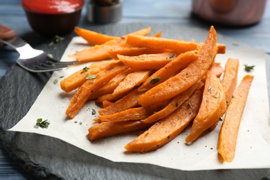 Photo of Tasty sweet potato fries on slate plate, closeup