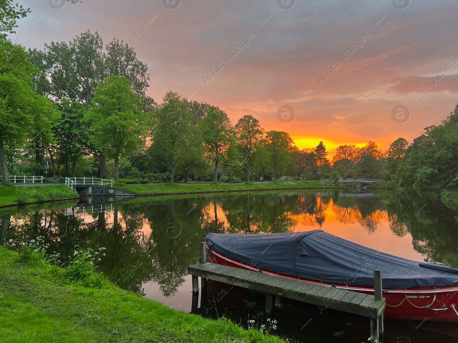 Photo of Scenic view of pond with moored boat at sunset