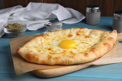 Photo of Fresh homemade khachapuri with cheese and egg on light blue wooden table