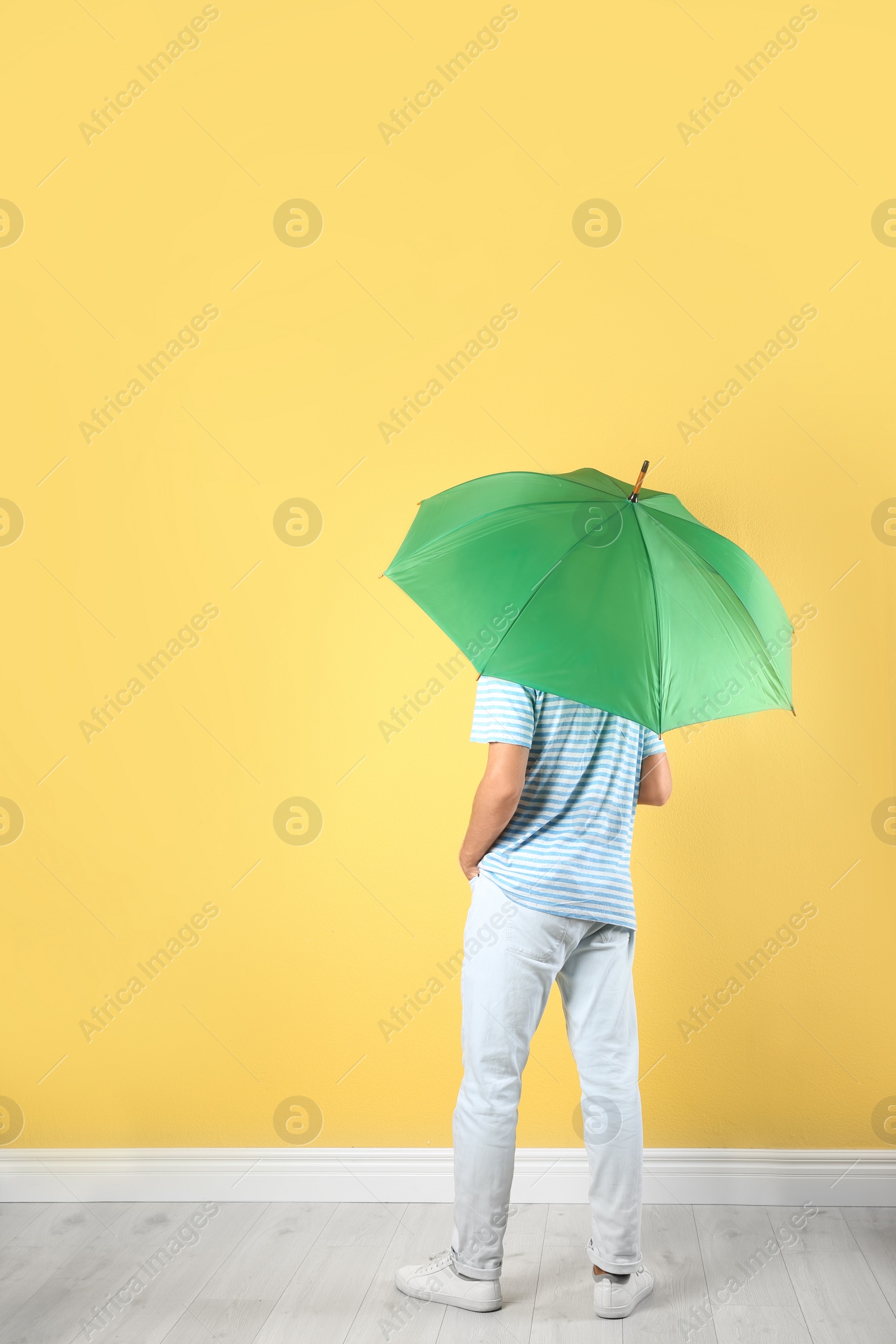 Photo of Man with green umbrella near color wall