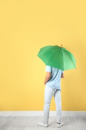 Man with green umbrella near color wall