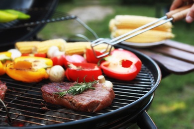 Photo of Man cooking on barbecue grill outdoors, closeup