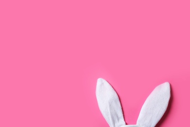 Photo of Funny Easter bunny ears on color background, top view with space for text