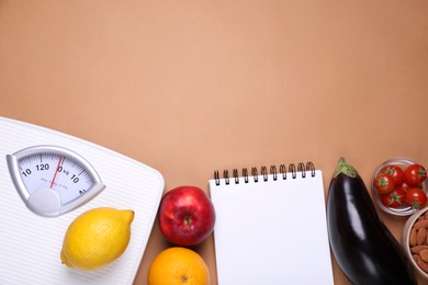 Photo of Scales, notebook, fresh fruits and vegetables on light brown background, flat lay with space for text. Low glycemic index diet