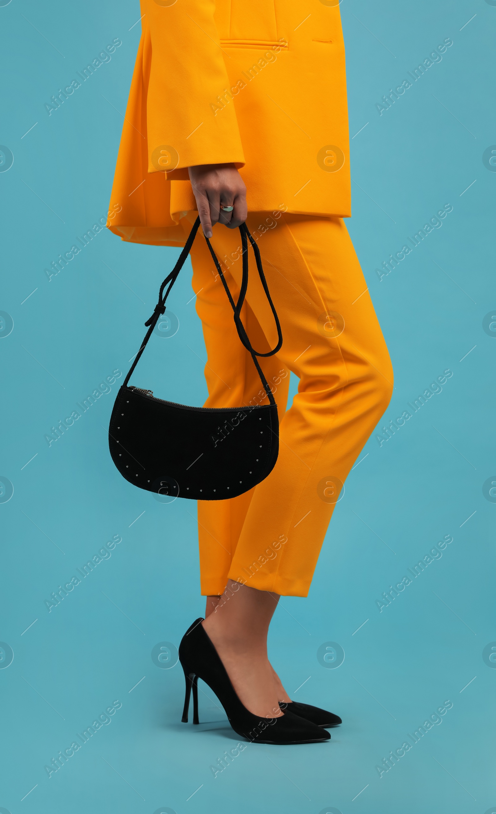 Image of Young woman wearing stylish orange clothes with bag on light blue background, closeup