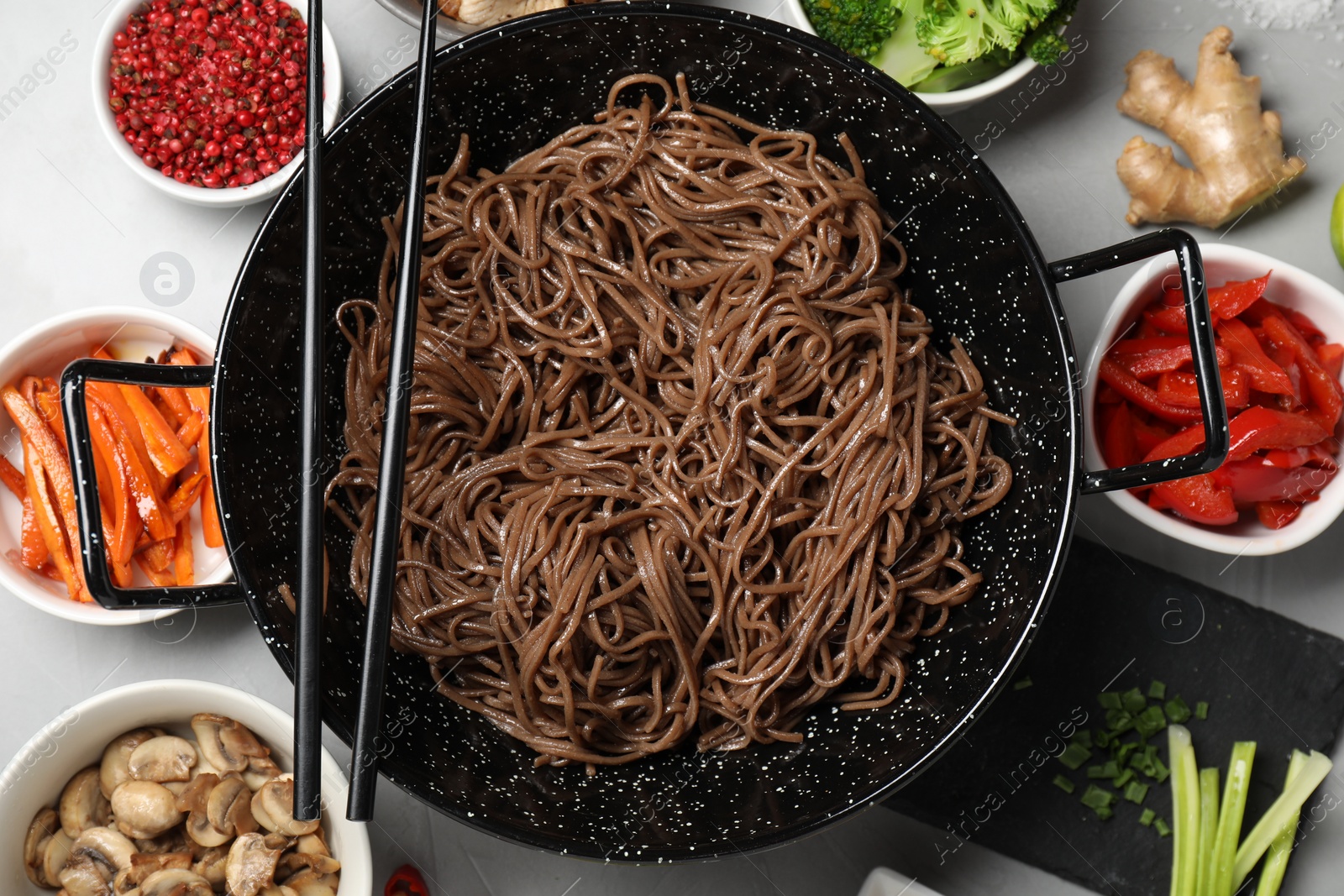 Photo of Wok with noodles, chicken and other products on light grey table, flat lay