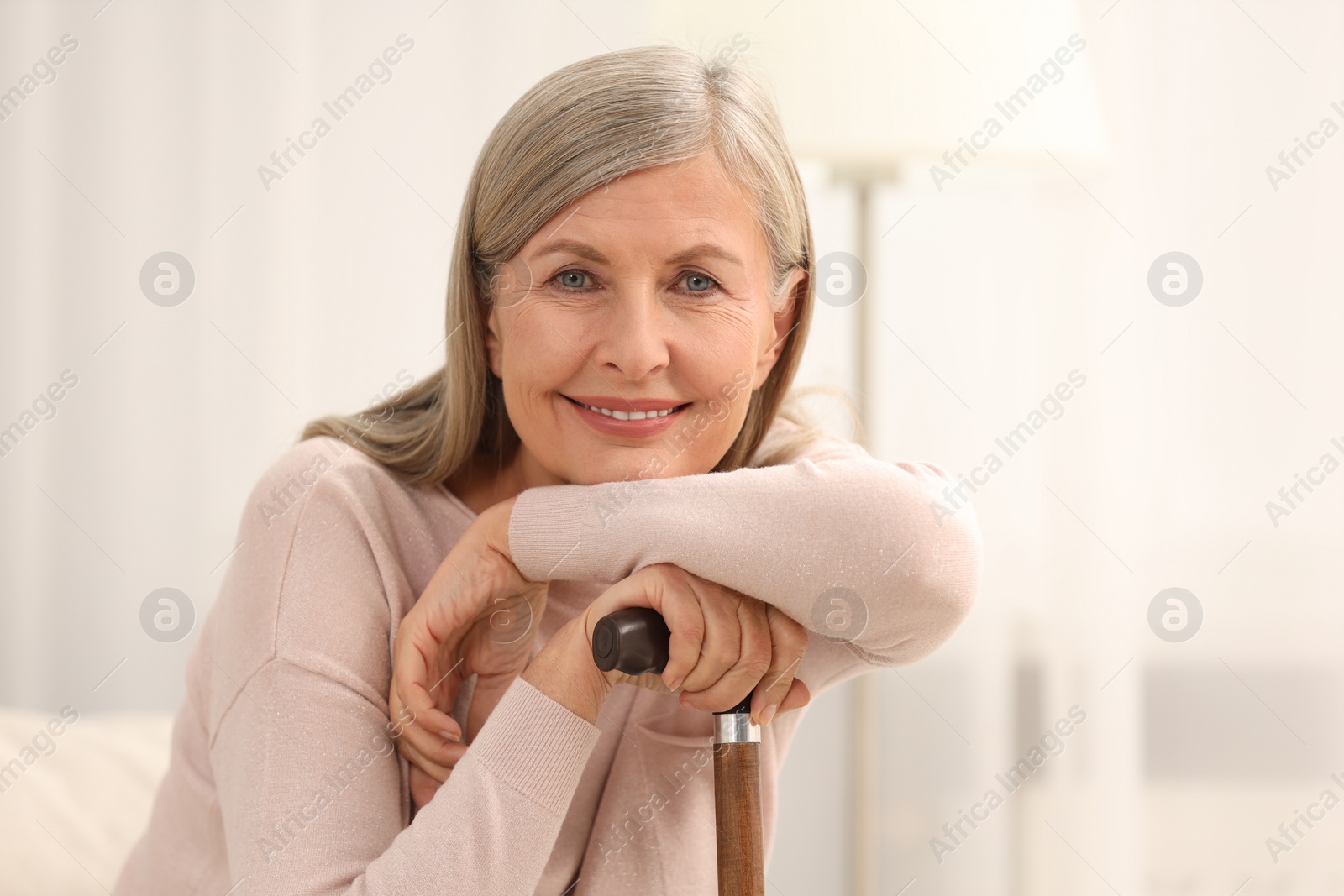 Photo of Beautiful mature woman with walking cane indoors