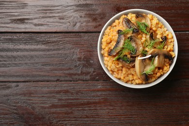 Photo of Delicious red lentils with mushrooms and dill in bowl on wooden table, top view. Space for text