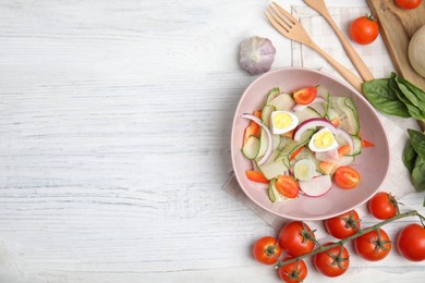 Bowl of delicious salad with ingredients on white wooden table, flat lay. Space for text