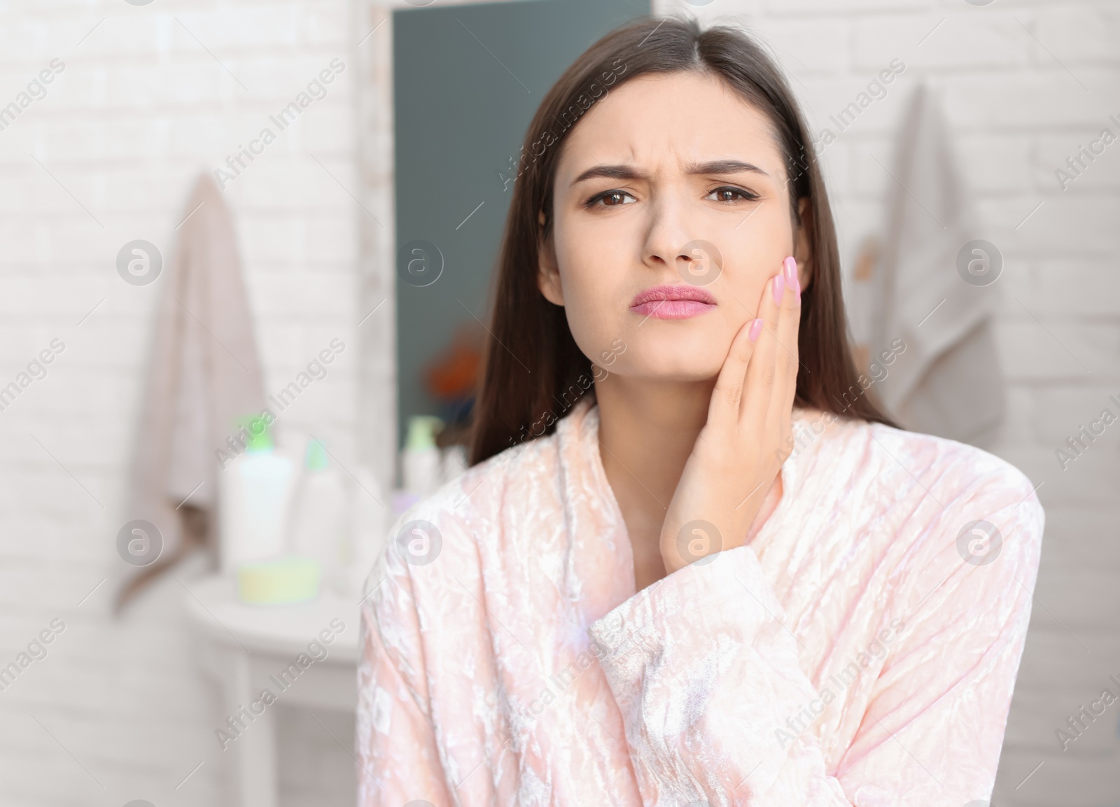 Photo of Young woman with sensitive teeth in bathroom