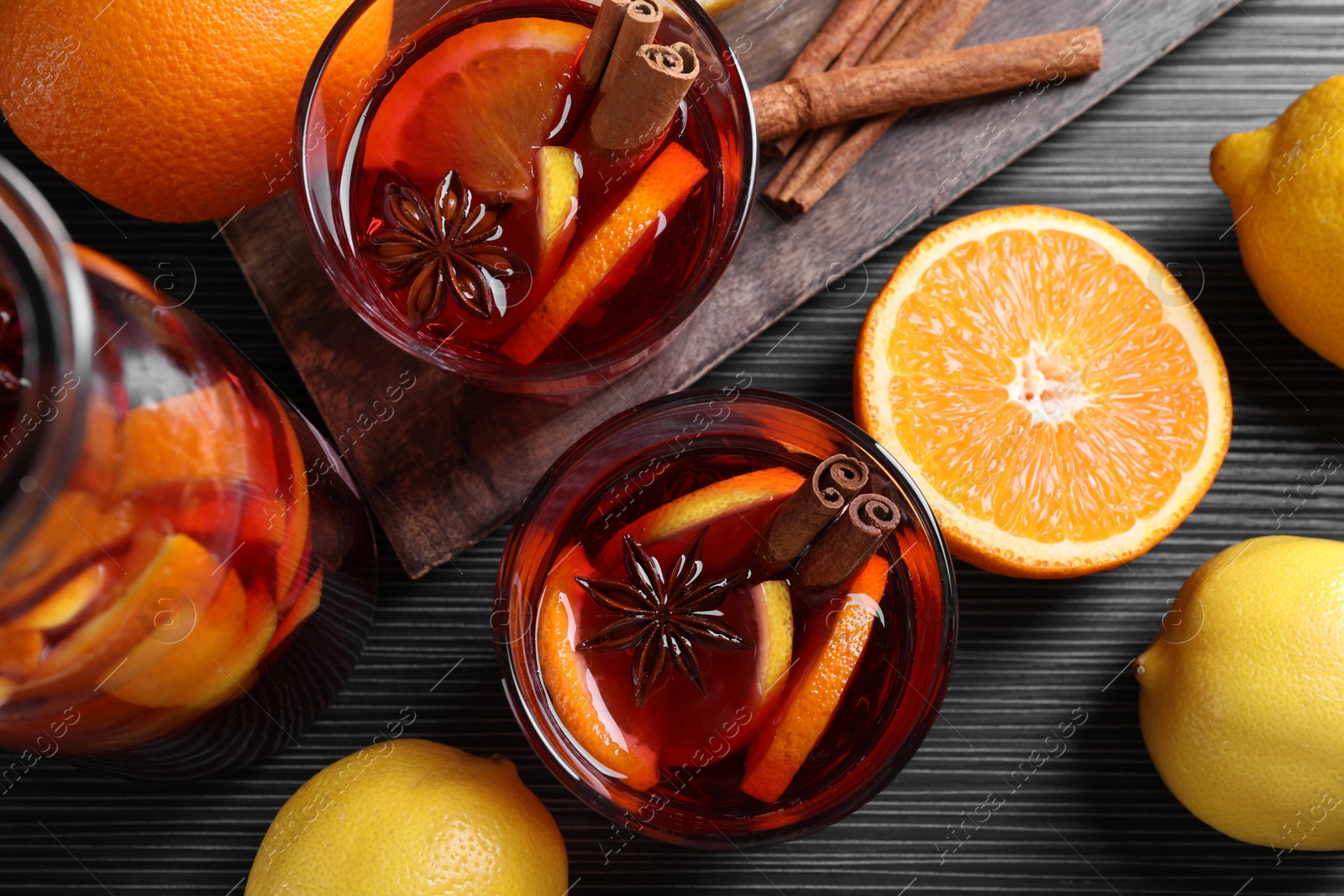 Photo of Aromatic punch drink and ingredients on black table, flat lay