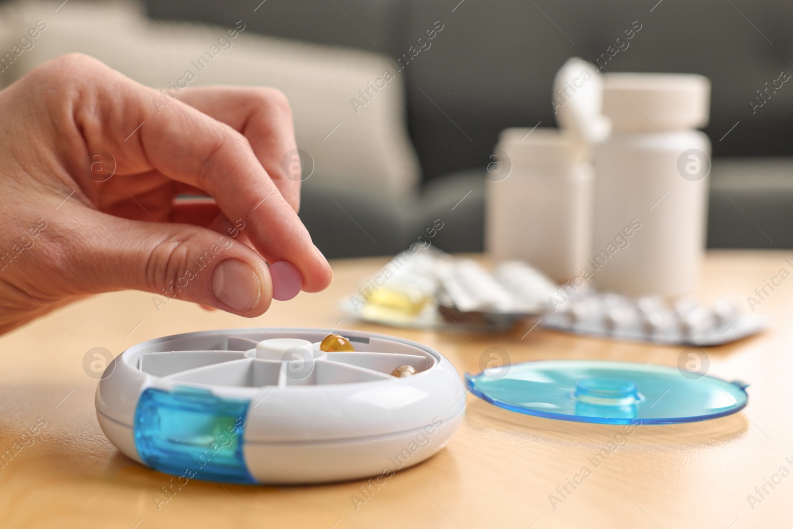 Photo of Woman with pills and organizer at light wooden table, closeup