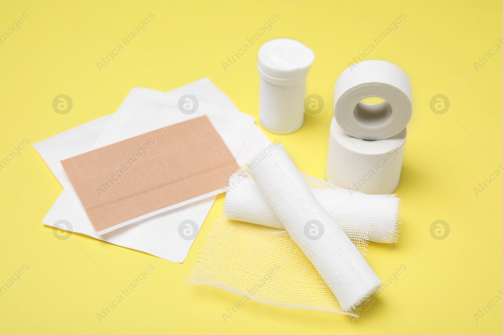 Photo of White bandage rolls and medical supplies on yellow background