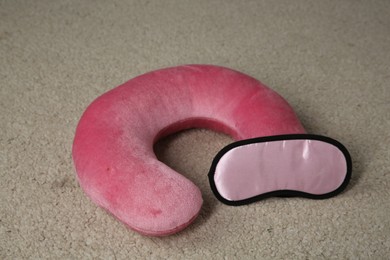 Photo of Pink travel pillow and sleep mask on beige rug