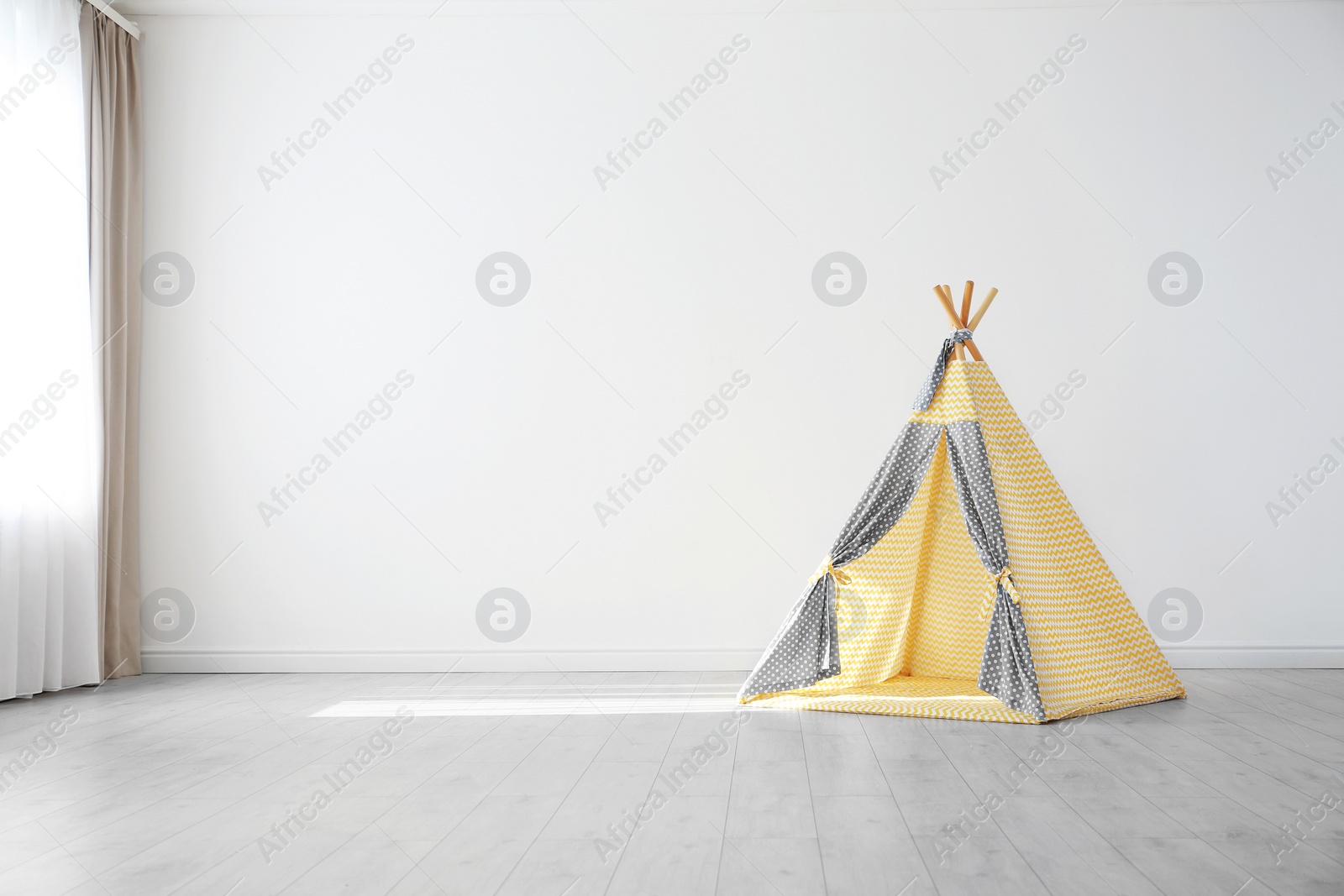 Photo of Cozy play tent for kids as element of nursery interior in empty room with space for text