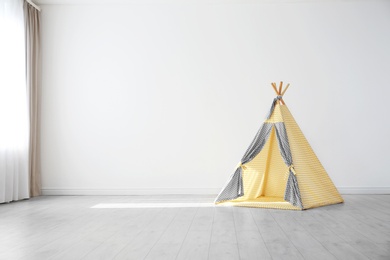 Photo of Cozy play tent for kids as element of nursery interior in empty room with space for text