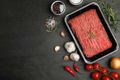 Photo of Raw fresh minced meat and other ingredients on black table, flat lay. Space for text