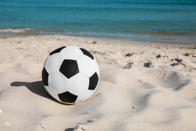 Soccer ball on beach, space for text. Football equipment