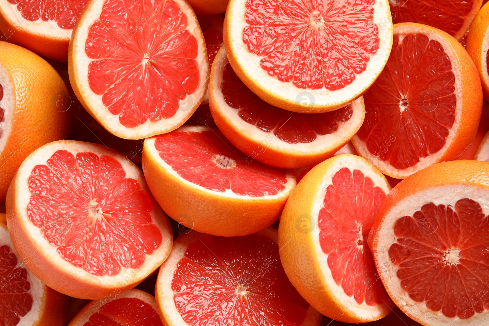 Photo of Many sliced fresh grapefruits as background, top view