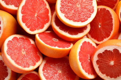 Many sliced fresh grapefruits as background, top view