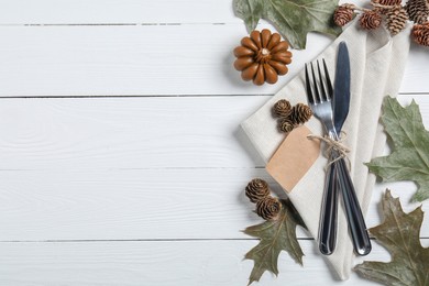Photo of Thanksgiving day table setting. Cutlery, napkin and autumn decoration on white wooden background, flat lay with space for text
