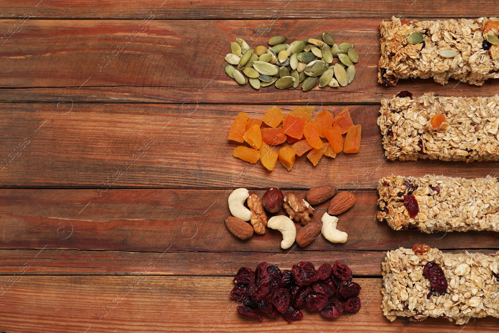 Photo of Different tasty granola bars and ingredients on wooden table, flat lay. Space for text