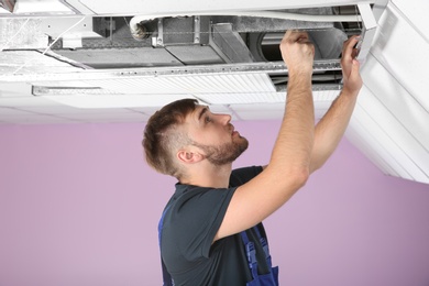 Photo of Young male technician repairing air conditioner indoors