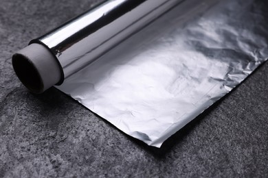 Roll of aluminum foil on grey table, closeup