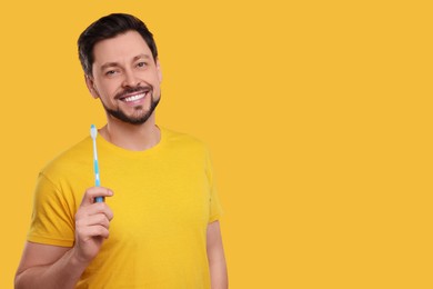 Photo of Man holding plastic toothbrush on yellow background. Space for text