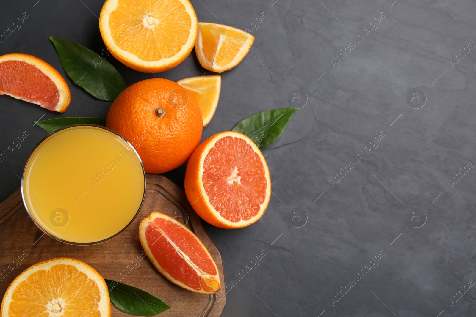 Photo of Delicious orange juice and fresh fruits on black table, flat lay. Space for text