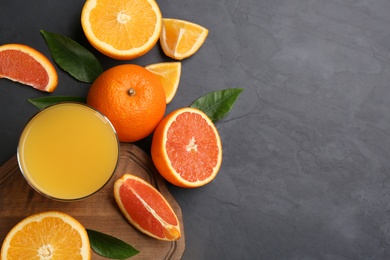 Photo of Delicious orange juice and fresh fruits on black table, flat lay. Space for text