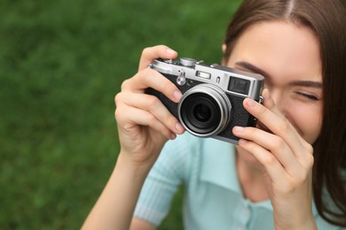 Young woman with camera taking photo outdoors, space for text. Interesting hobby