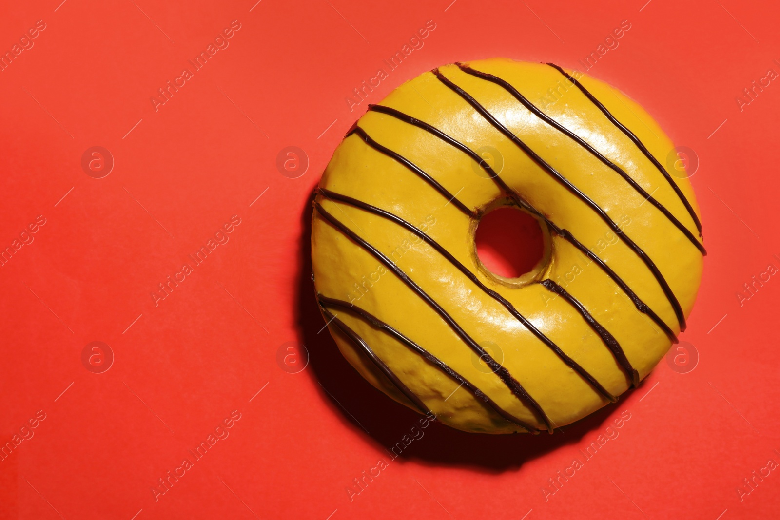 Photo of Sweet tasty glazed donut on coral background, top view. Space for text