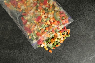 Zip bag with different frozen vegetables on grey table, top view