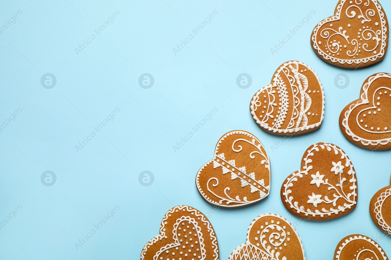 Photo of Tasty heart shaped gingerbread cookies on light blue background, flat lay. Space for text