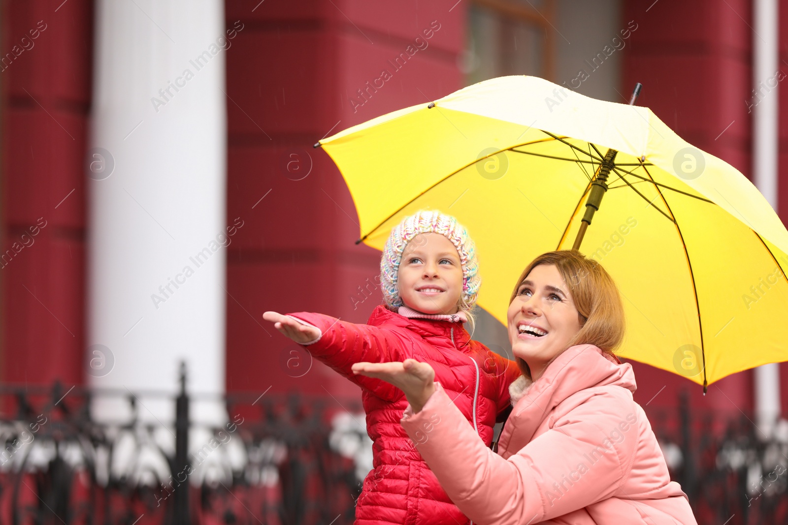 Photo of Mother and daughter with umbrella in city on autumn rainy day