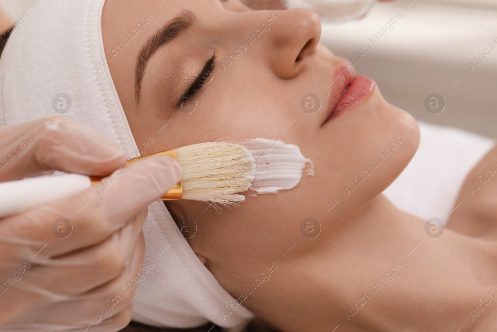 Photo of Young woman during face peeling procedure in salon, closeup