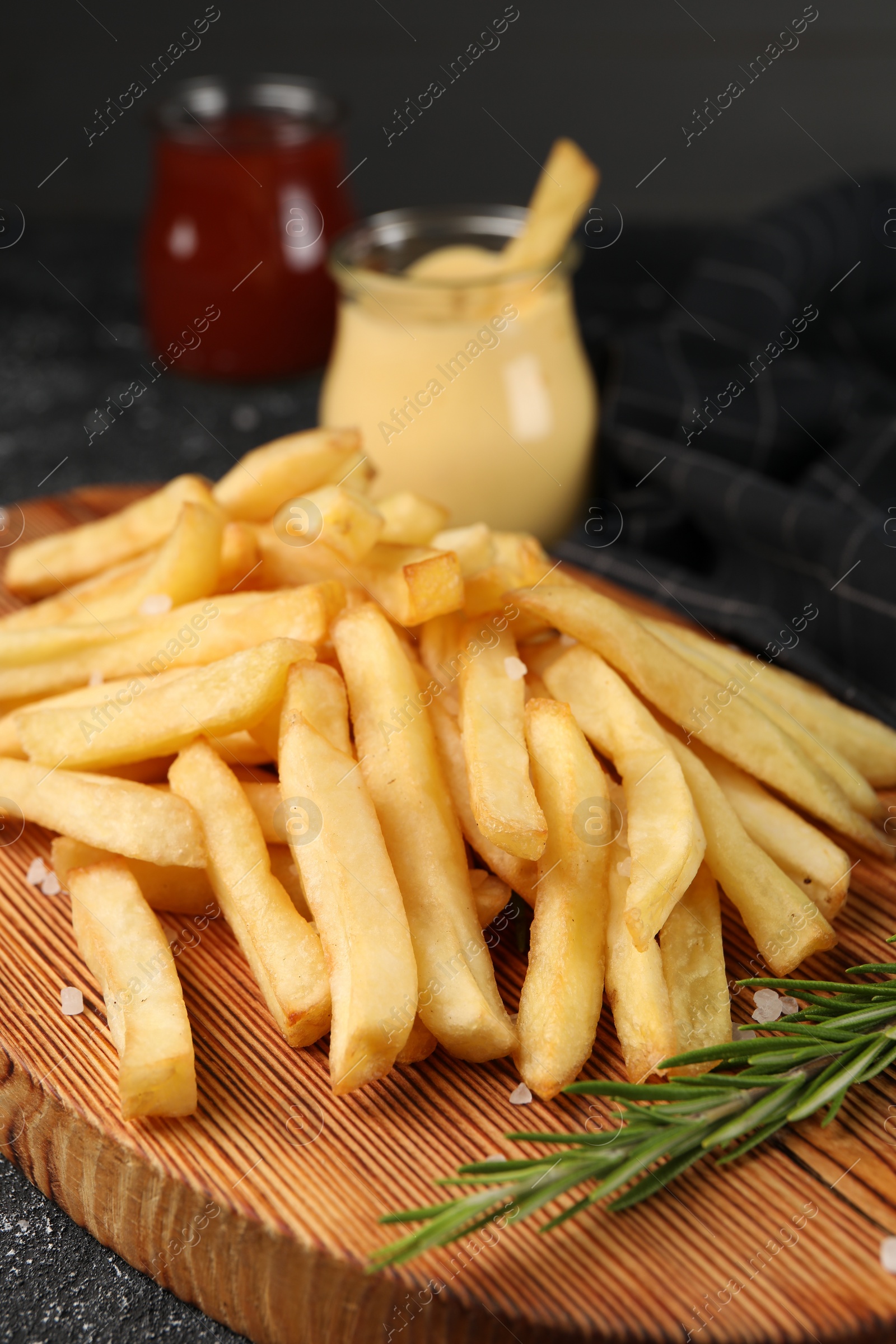 Photo of Delicious french fries with rosemary on grey table, closeup