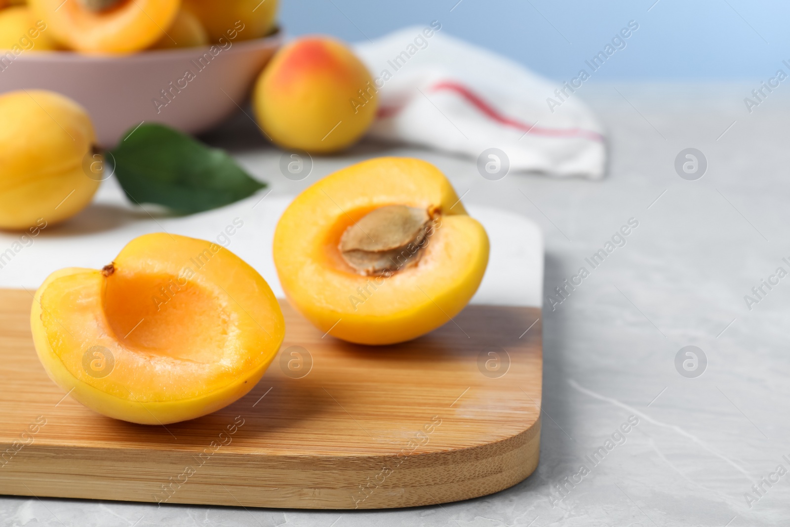 Photo of Halves of delicious fresh ripe apricot on grey table. Space for text