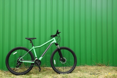 Modern bicycle near green metal fence outdoors. Space for text