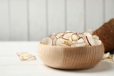 Photo of Tasty coconut chips on white wooden table