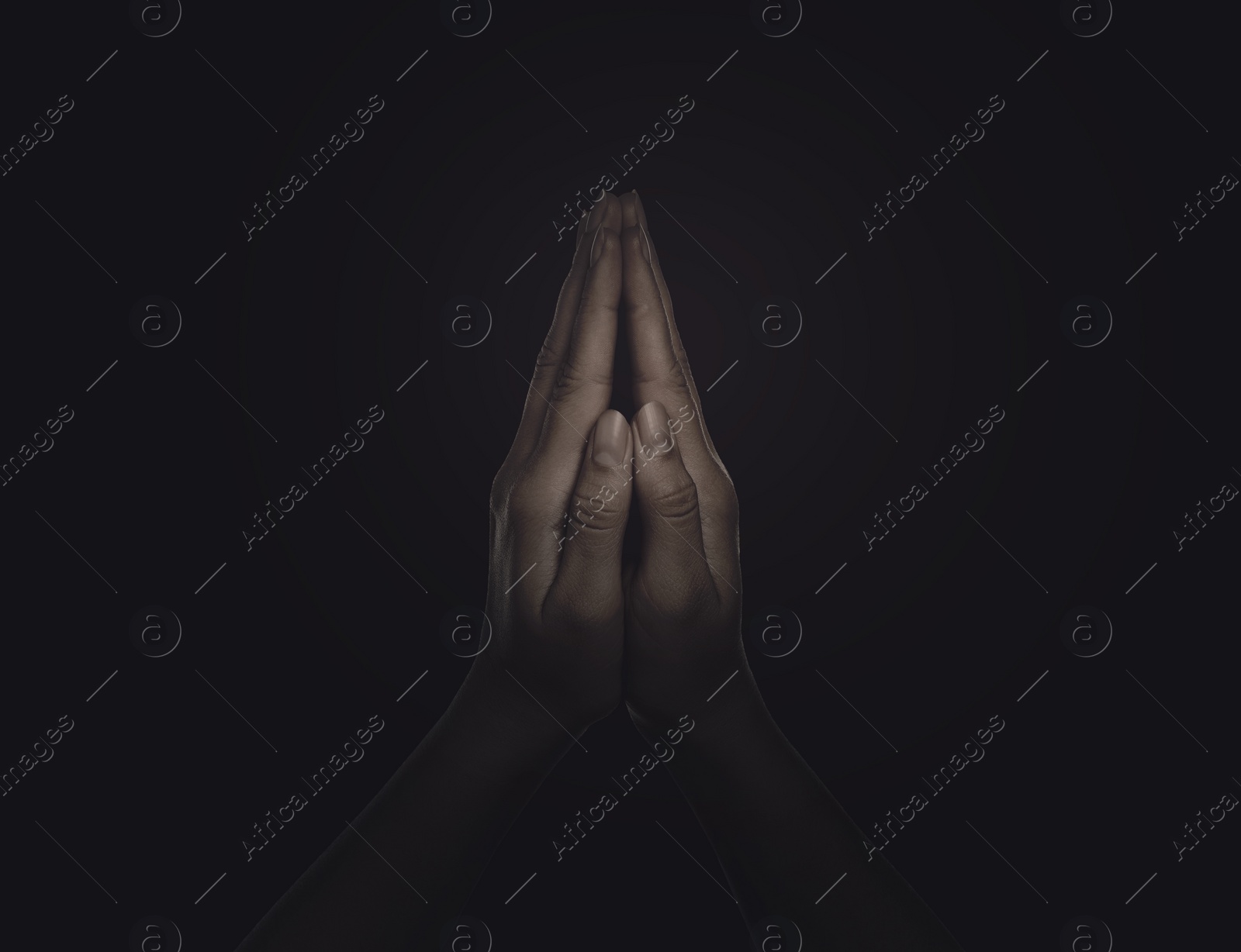 Image of Christian woman praying in darkness, closeup. Belief