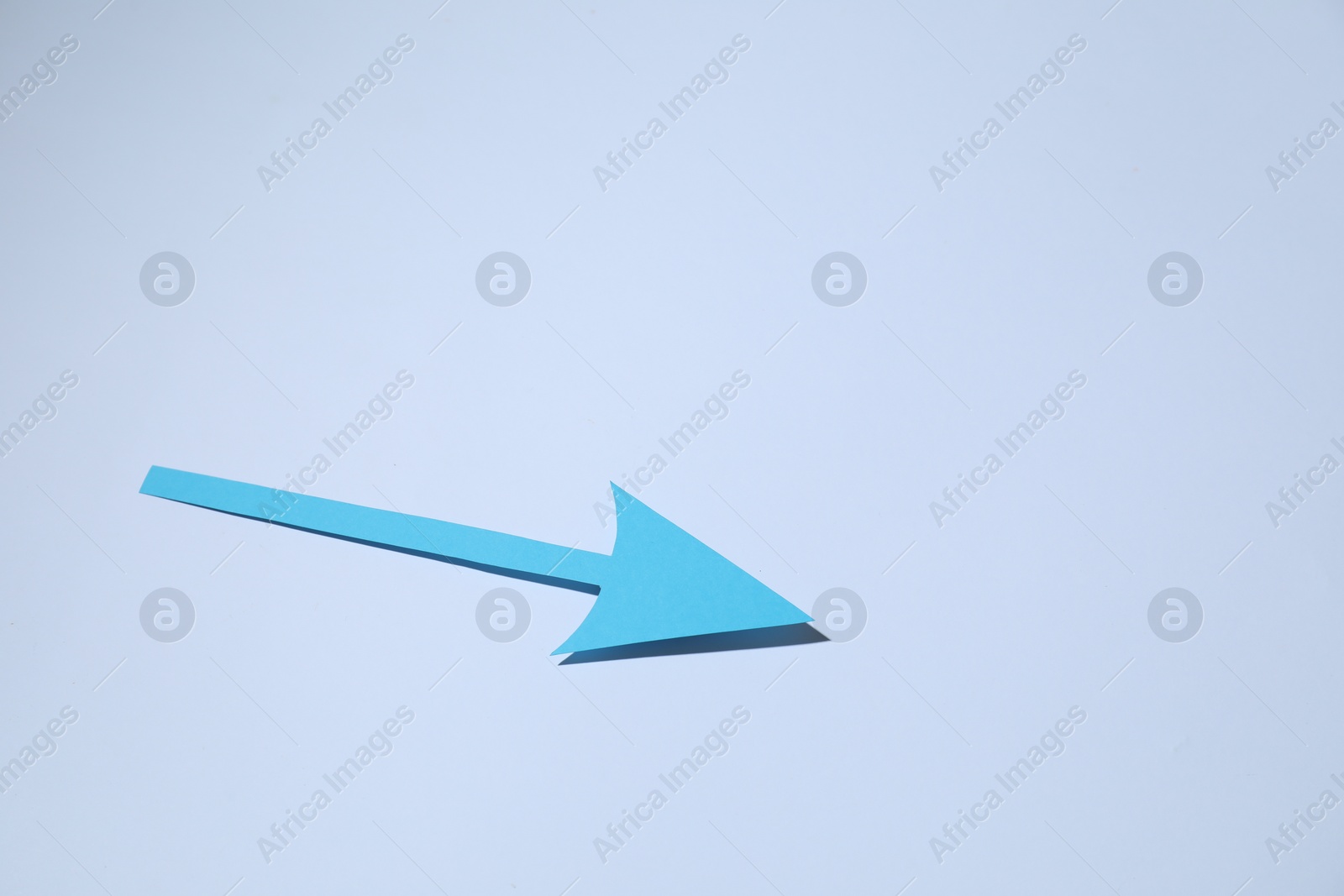 Photo of Light blue paper arrow on white background, space for text