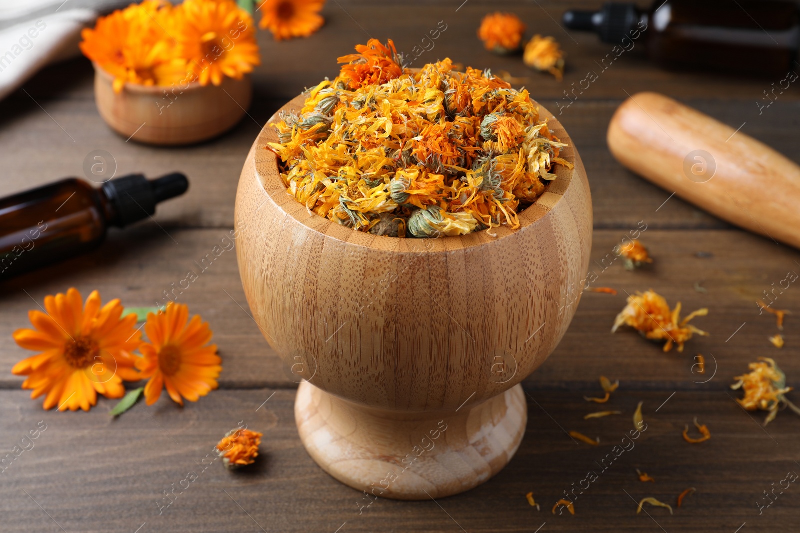 Photo of Mortar of dry calendula flowers on wooden table