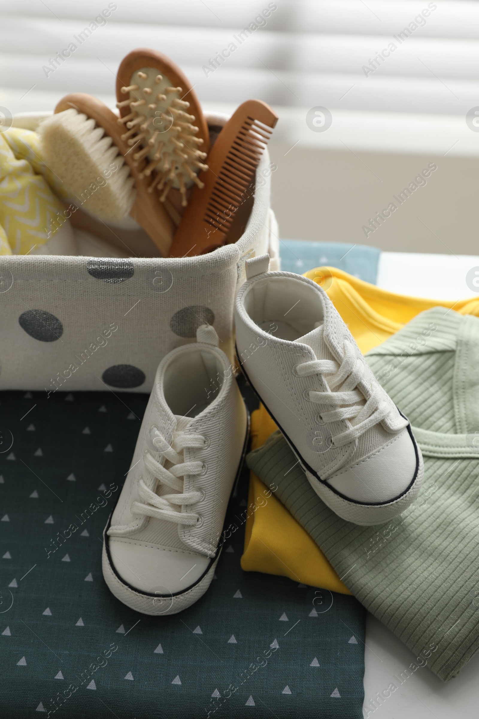 Photo of Baby clothes, shoes and accessories near window indoors